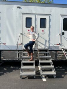 A woman standing on some steps in front of a trailer.