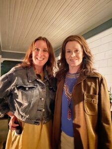 Two women standing next to each other in front of a building.